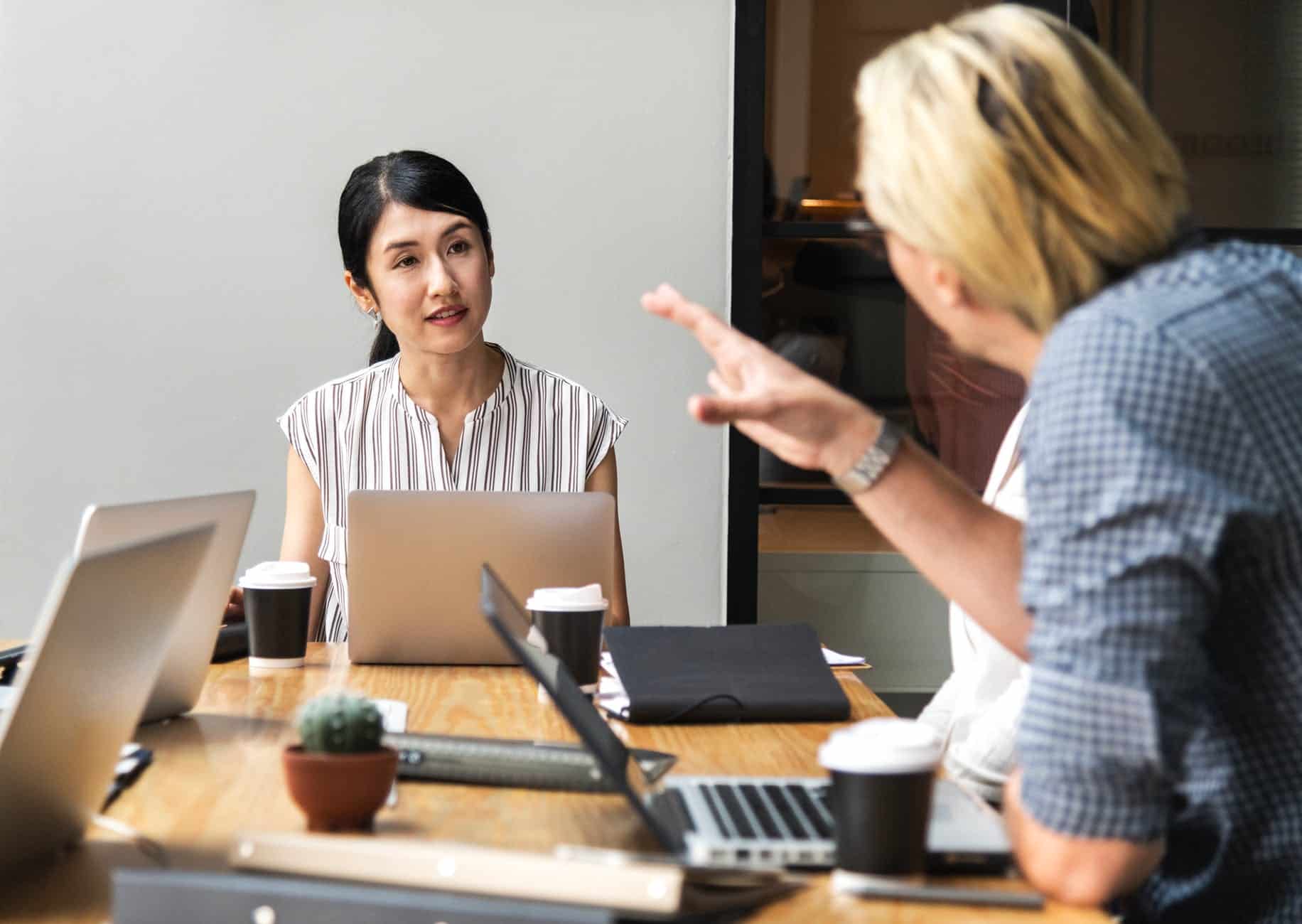 men talking to a woman sitting in front of silver laptop computer