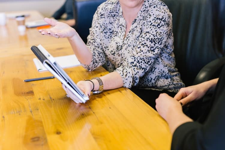 two person having a conversation while holding a tablet