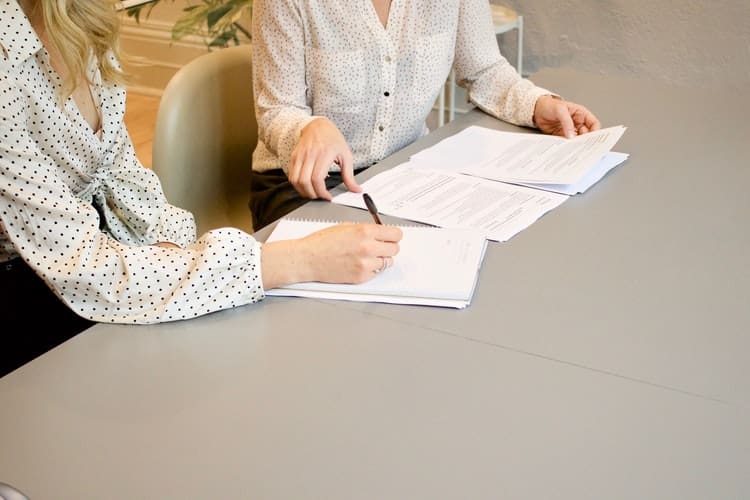 two person reading and writing down some notes